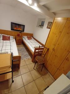 Habitación con 2 camas, silla y TV. en Harmónia Parasztház és Apartman, en Poroszló