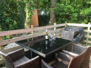 a table and chairs with a bottle of wine on a fence at Pebbles Seaside Lodge in Kent