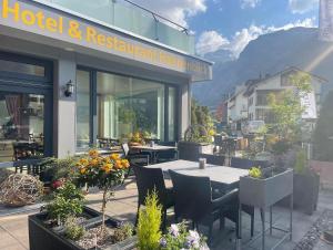 Un restaurante con mesas y sillas frente a un edificio. en Hotel Hahnenblick, en Engelberg