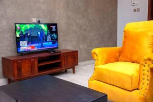 un soggiorno con TV e divano giallo di Secure cozy getaway near Kampala business district a Kampala