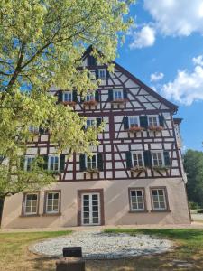 ein Fachwerkhaus in einem Park mit einem Baum in der Unterkunft OSCARS Hotel 1415 in Bad Liebenzell