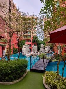a bridge over a pool in a courtyard with trees at Seven Seas Condo Resort Jomtien in Jomtien Beach