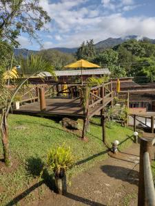 eine Holzterrasse mit einem Tisch und einem Sonnenschirm in der Unterkunft Chale Disco de Arado in Visconde De Maua