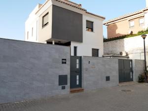 ein weißes Gebäude mit einer schwarzen Tür neben einer Wand in der Unterkunft Apartamento ALDAMY in Granada