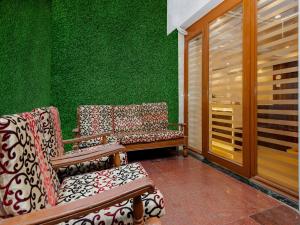 duas cadeiras sentadas ao lado de uma parede verde em Hotel KGN - Mumbai em Mumbai