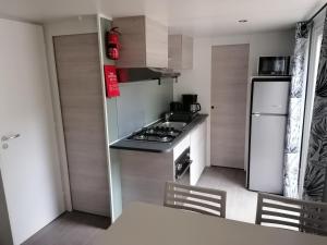 uma pequena cozinha com um fogão e um frigorífico em Mobil Home 4-6 personnes em Gastes