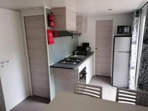 a small kitchen with a stove and a refrigerator at Mobil Home 4-6 personnes in Gastes