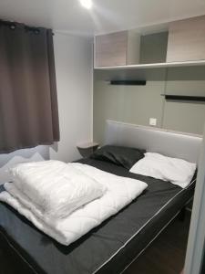 een bed met witte kussens in een kamer bij Mobil Home 4-6 personnes in Gastes