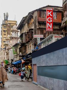 a group of people walking down a street with buildings at Hotel KGN - Mumbai in Mumbai