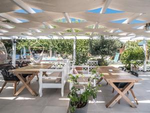 a patio with wooden tables and chairs under a white umbrella at Georgia's Garden by Omilos Hotels in Amoudara Herakliou
