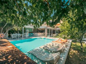 une femme assise sur des chaises longues à côté d'une piscine dans l'établissement Georgia's Garden by Omilos Hotels, à Amoudara