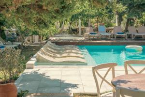 einen Pool mit Stühlen, einem Tisch und Bäumen in der Unterkunft Georgia's Garden by Omilos Hotels in Ammoudara