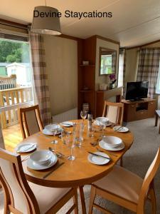 a wooden table with plates and wine glasses on it at Devine Staycations at 38 Riverside in Hawick