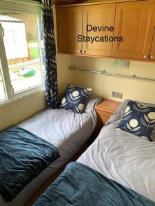 two beds in a small room with a window at Devine Staycations at 38 Riverside in Hawick