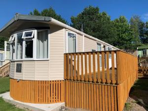 a small house with a gate and a fence at 2 Bed Caravan - Sleeps 6 - Pets - River Teviot in Hawick