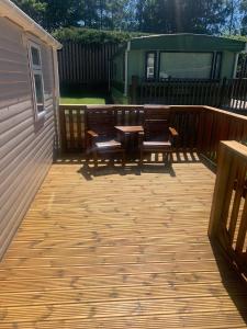 a patio with two benches and a table on a deck at Devine Staycations at 38 Riverside in Hawick