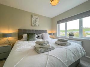 um quarto com uma grande cama branca com toalhas em 'Benson View' - 2 bedroom Lake District home em Kendal
