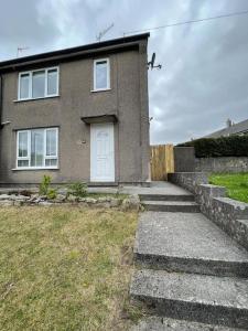 a brick house with a white door and a yard at 'Benson View' - 2 bedroom Lake District home in Kendal