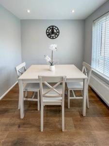 a white table and chairs with a clock on the wall at 'Benson View' - 2 bedroom Lake District home in Kendal