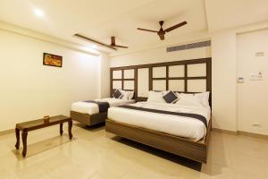 a bedroom with two beds and a table at Hotel Comfort Park - Opposite Sri Ramachandra Medical College Porur in Chennai