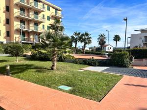 un parco con una palma di fronte a un edificio di Appartamento Incantevole a 100metri dal mare e vicino a pista ciclabile a Imperia
