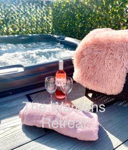 The Wardens Retreat - Tattershall Lakes Country Park في تاتيرشال: حوض استحمام ساخن مع زجاجة من النبيذ وكأسين