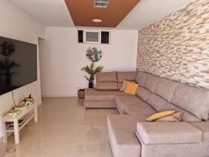 ein Wohnzimmer mit einer Couch und einer Ziegelwand in der Unterkunft Fantástica Villa Cusmano con piscina privada in Adeje