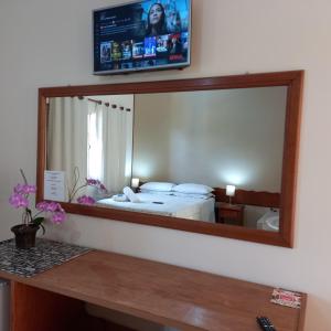 een spiegel die een slaapkamer reflecteert met een bed en een tv bij Miragem Chalés in Serra Negra