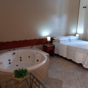 a bathroom with a bath tub next to a bed at Miragem Chalés in Serra Negra