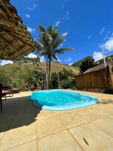 a blue swimming pool on a patio with a palm tree at Peniel do Sana Guest House in Sana