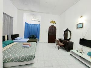 Dormitorio con cama, escritorio y TV en Rumah Rehat QNM Holidays en Kuala Terengganu