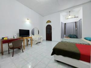 Dormitorio con cama, escritorio y TV en Rumah Rehat QNM Holidays en Kuala Terengganu