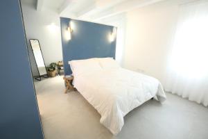 1 dormitorio con cama blanca y pared azul en AGATOPISTO Animo Salmastro, en Comacchio