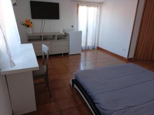 Habitación con cama, mesa y TV. en Al Centro Storico - Holiday House, en Vibo Valentia