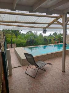 una sedia seduta su un patio accanto alla piscina di Gîtes La Troisième Chute a Capesterre-Belle-Eau