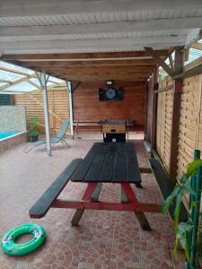 a picnic table on a patio with a table and chairs at Gîtes La Troisième Chute in Capesterre-Belle-Eau