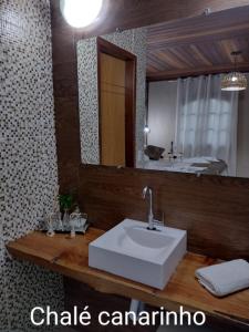 uma casa de banho com um lavatório branco e um espelho. em Chale Disco de Arado em Visconde de Mauá