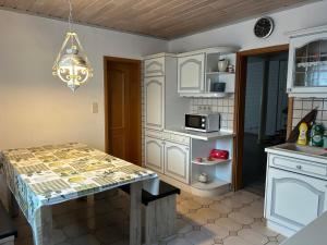 a kitchen with white cabinets and a table at Parkplätze, Einzelbetten, 2 TVs, Balkon, Terrasse, fast Wi-Fi bis zu 1000 Mbit, Homeoffice in Rodenbach