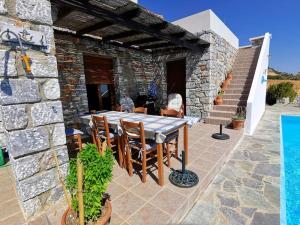 una casa in pietra con tavolo e sedie su un patio di Villa Mavri Ruhige private Pool Villa, Meerblick ad Agia Paraskevi
