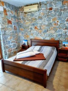 a bed in a room with a stone wall at Villa Mavri Ruhige private Pool Villa, Meerblick in Agia Paraskevi