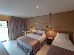 um quarto de hotel com duas camas e uma janela em Hotel Coco Beach em Conde