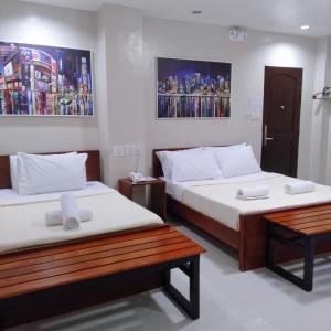 a room with two beds and a bench in it at Grace & RB Hotel in Kalibo