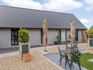 eine Terrasse mit einem Tisch, Stühlen und Sonnenschirmen in der Unterkunft dairy cottages in Wimborne Minster