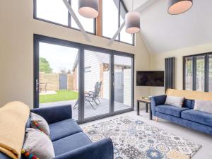 a living room with blue couches and a sliding glass door at dairy cottages in Wimborne Minster