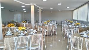 a banquet hall with tables and chairs with yellow flowers at Goldmen Hotel in Cianorte