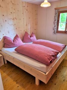 una camera da letto con un letto con cuscini rossi e bianchi di Haus Rheintalblick a Übersaxen