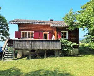 a log house with a porch and a woman standing on the balcony at Haus Rheintalblick in Übersaxen