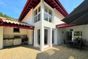 a house with a patio with a table and a kitchen at Villa Paulen Pausa in Uhart-Cize