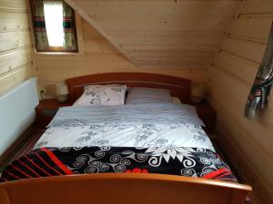 a small bed in a wooden cabin with a window at U Garczków in Witów