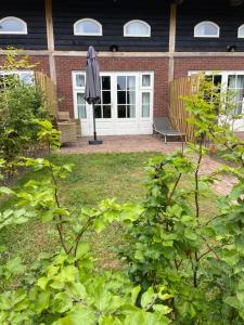 einen Garten mit einem Sonnenschirm und einem Stuhl vor einem Haus in der Unterkunft De Citadel - De Boomgaard in Markelo